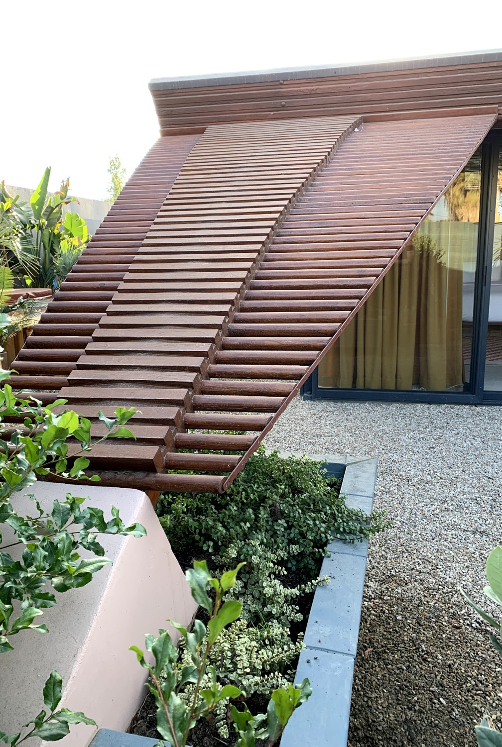 Rehabilitated wood trellis, extending off southern side of the roof, concrete planter and buttress